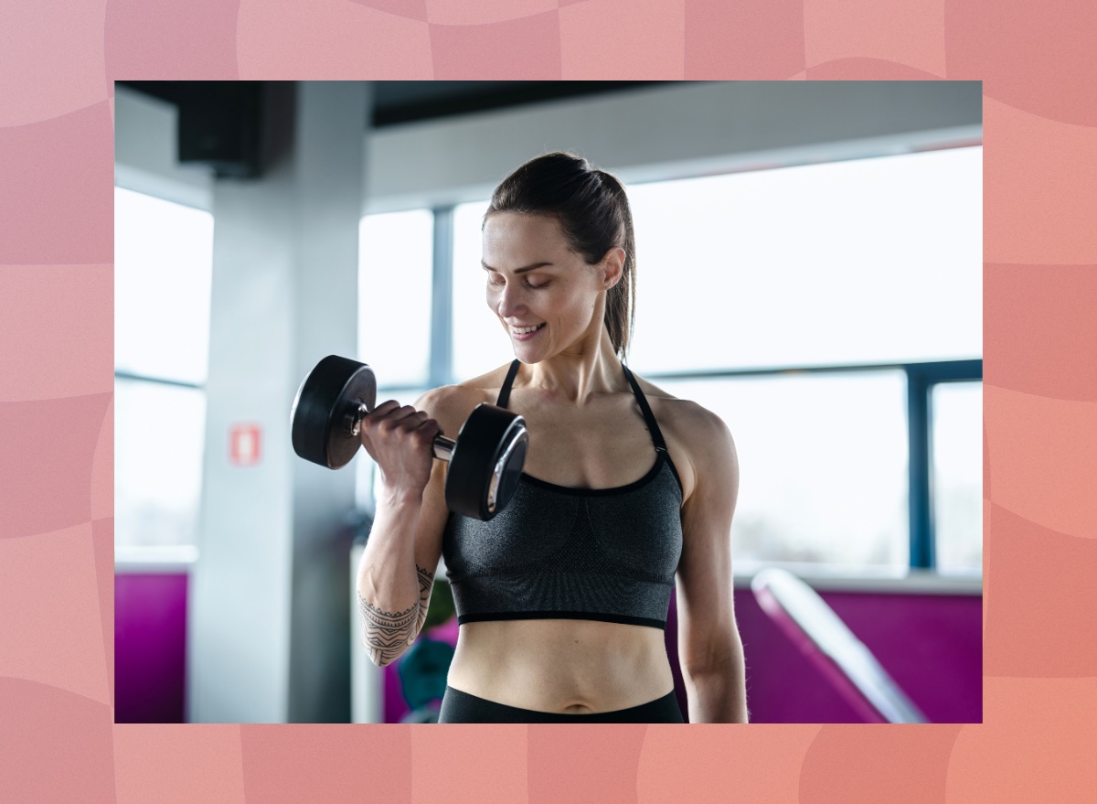 brunette woman in sports bra lifting dumbbell at the gym