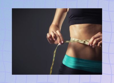 close-up of woman in sports bra and yoga pants measuring her waistline