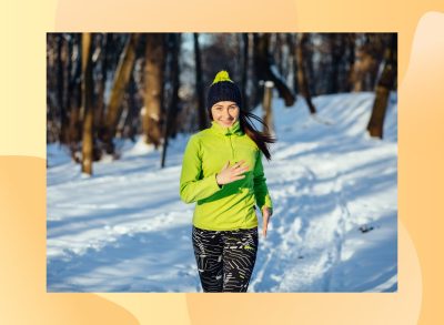 happy brunette woman running in the snow for exercise on winter day