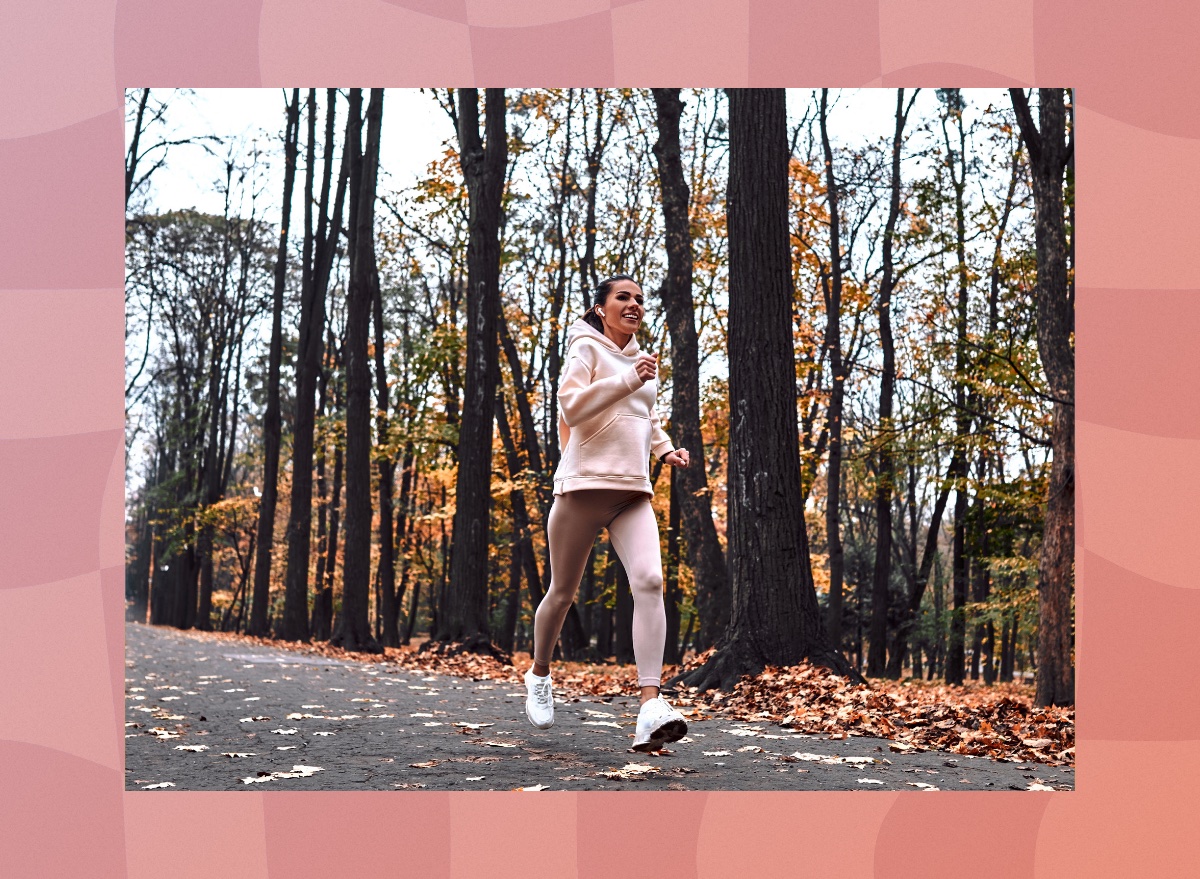 brunette woman running outdoors on trail in the fall with leaves on the ground