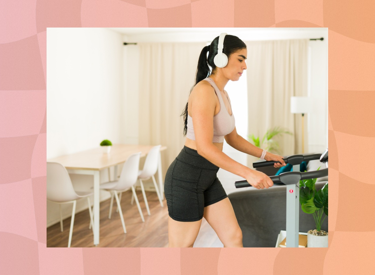 focused brunette woman walking on treadmill in bright apartment