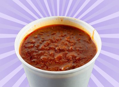 A white cup filled to the brim with chili set against a vibrant background.