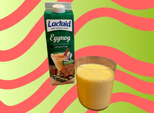 A carton of Lactaid eggnog beside a glass of the beverage set against a festive background