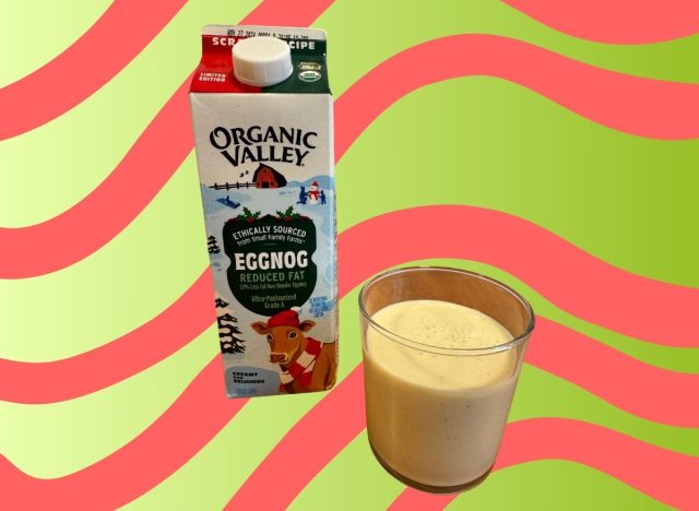 A carton of Organic Valley eggnog beside a glass of the beverage set against a festive background.