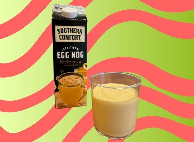 A carton of Southern Comfort-brand eggnog beside a glass of the beverage set against a festive background