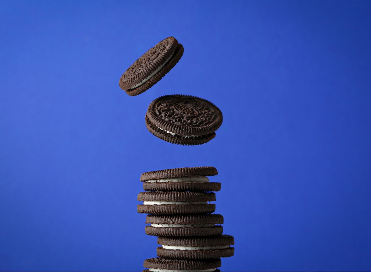 Oreo cookies falling on a pile in front of blue background