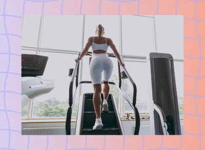 backside view of woman doing a stair climber workout at the gym in front of windows