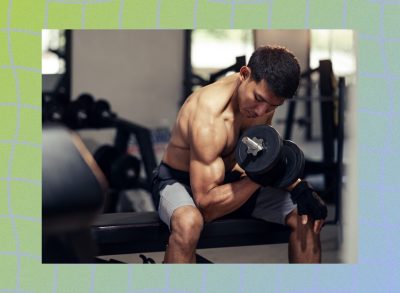 muscular fitness man doing bicep curls in weight room at the gym