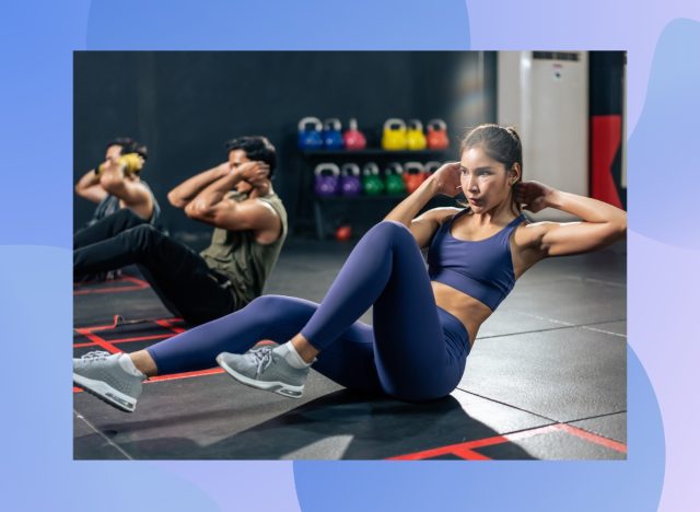 focused brunette woman doing bicycle crunches in workout class