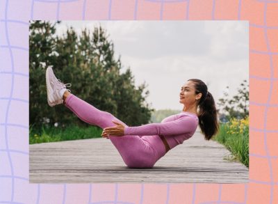 fit brunette woman in pink activewear set doing boat pose on boardwalk walkway