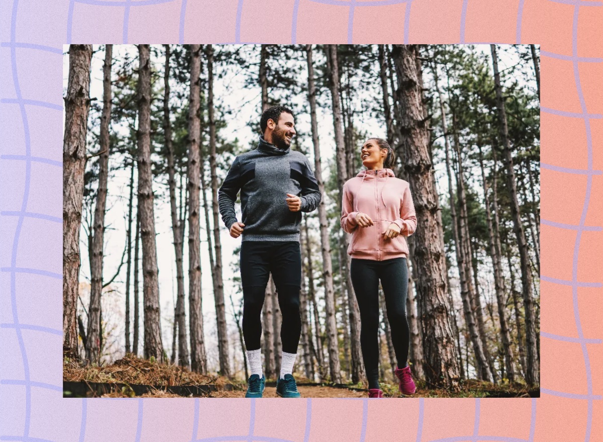 fit couple smiling and looking at each other as they prepare to go for a light jog or brisk walk in the woods