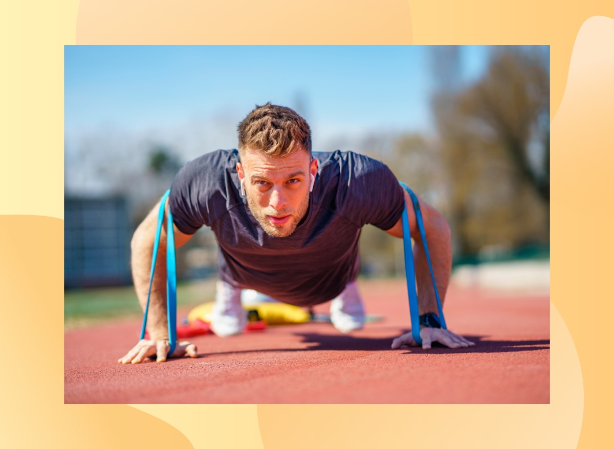 fit, focused man doing resistance band pushup on track outdoors