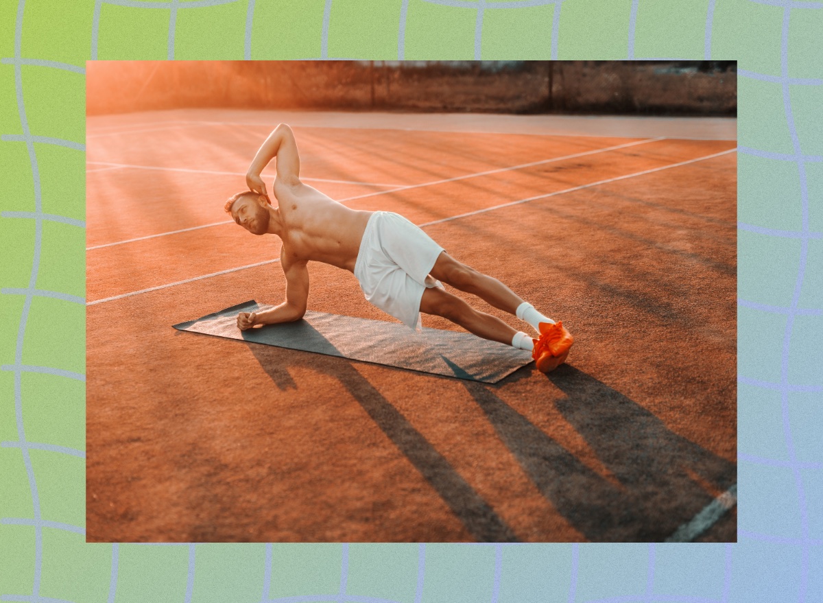 fit man doing a side plank on mat on court while sun sets