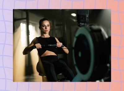 fit, focused woman doing rowing workout in dark gym