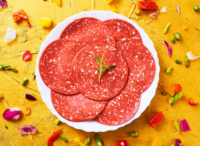 high angle view of some slices of veggie salami in a plate, on a golden textured surface