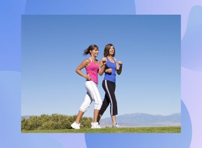 two fit women walking for exercise through scenic field trail