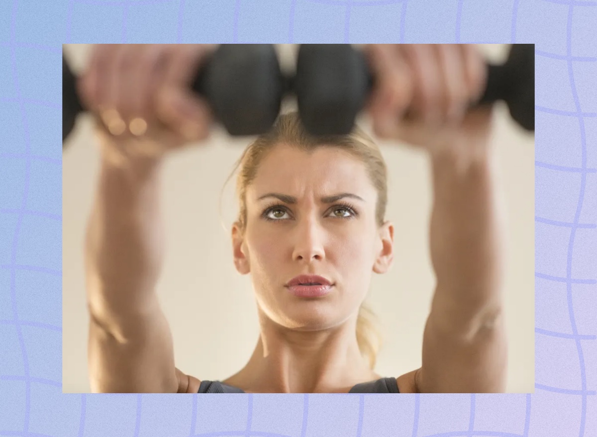 fit, determined woman lifting dumbbells