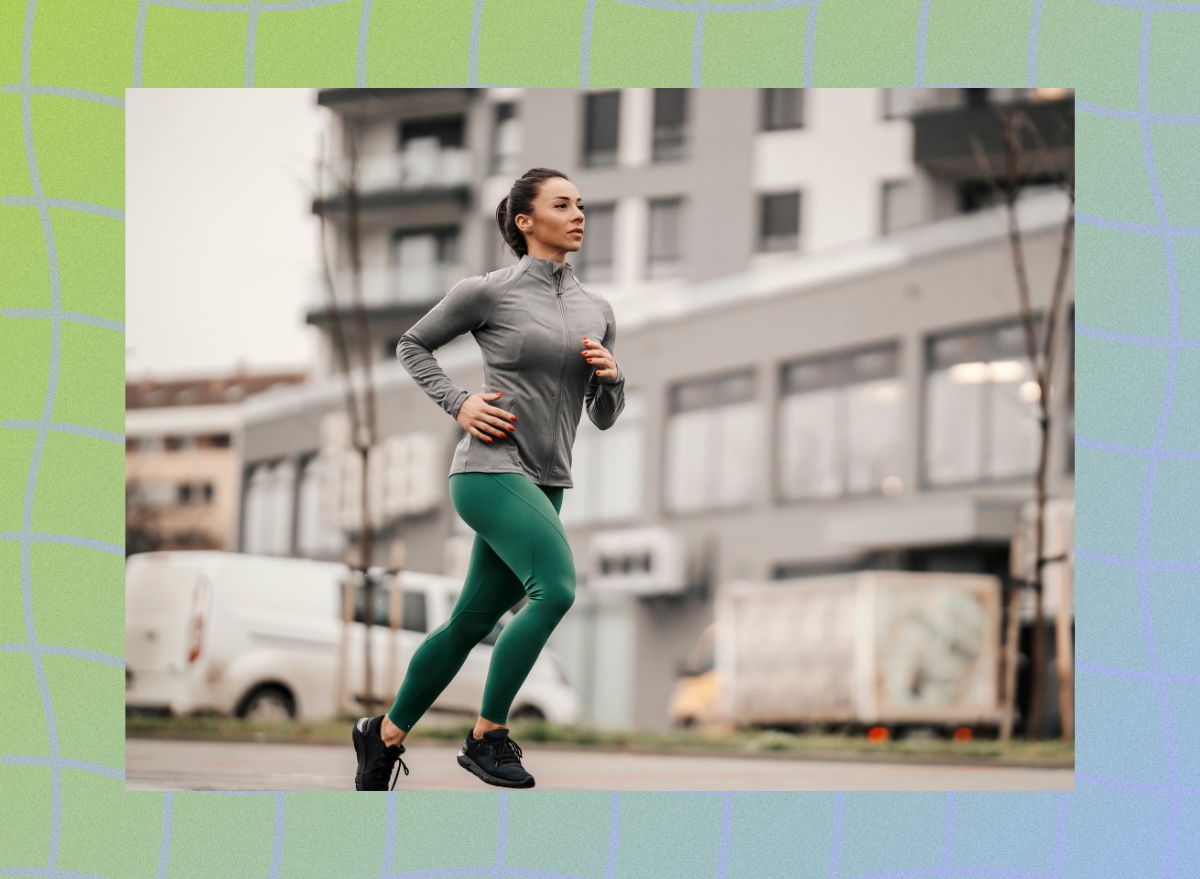 fit brunette woman running outdoors on winter day with city backdrop blurred behind her