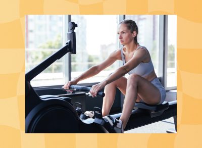 fit woman using rowing machine at gym next to windows