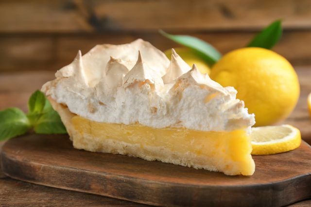 Piece of yummy lemon meringue pie on wooden table.