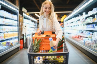 Young cool customer woman wear casual clothes shopping at supermaket store grocery shop buying with trolley cart choose products inside hypermarket.