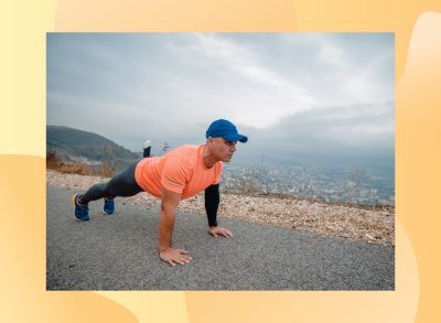 fit, mature man doing high plank or pushups on side of the road with mountains in the background