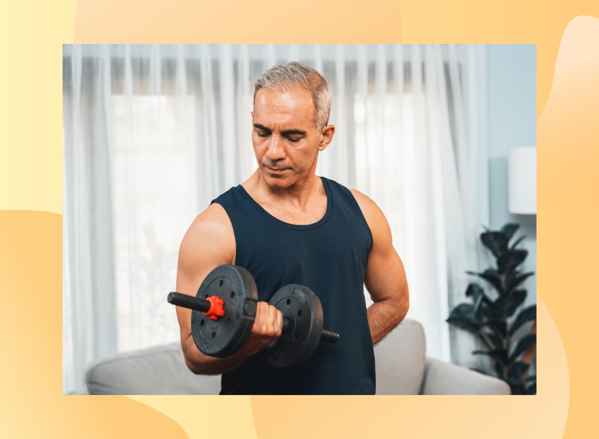 fit, mature man doing bicep curl in living space in front of couch and curtains