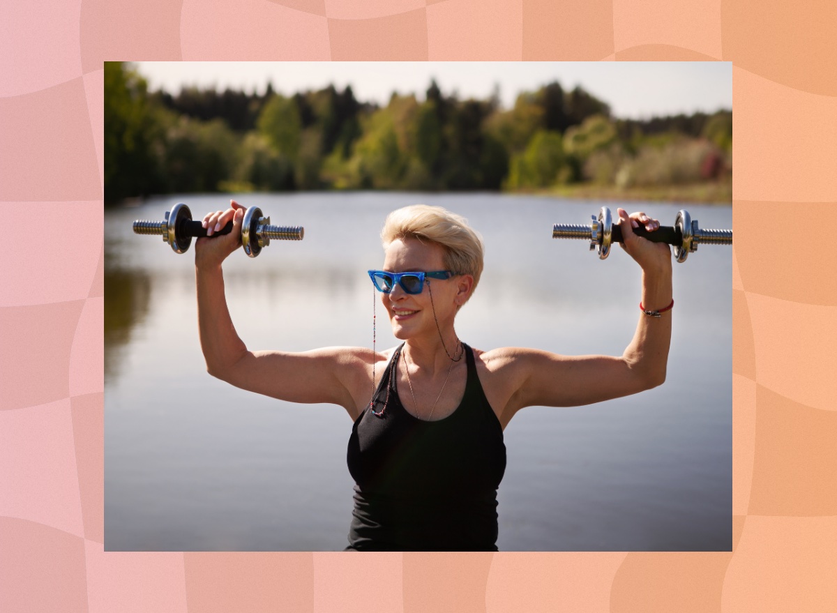 fit, mature blonde woman lifts dumbbells by a lake on a sunny day