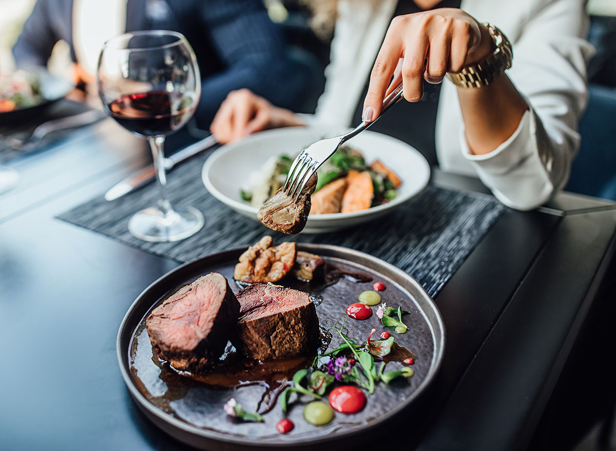 Close up photo, woman ready to eat medium rare beef steak while sitting in modern restaurant.