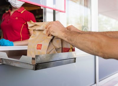 McDonalds service the Drive-Thru due to coronavirus. Employee in gloves, order in window. Contactless transfer.