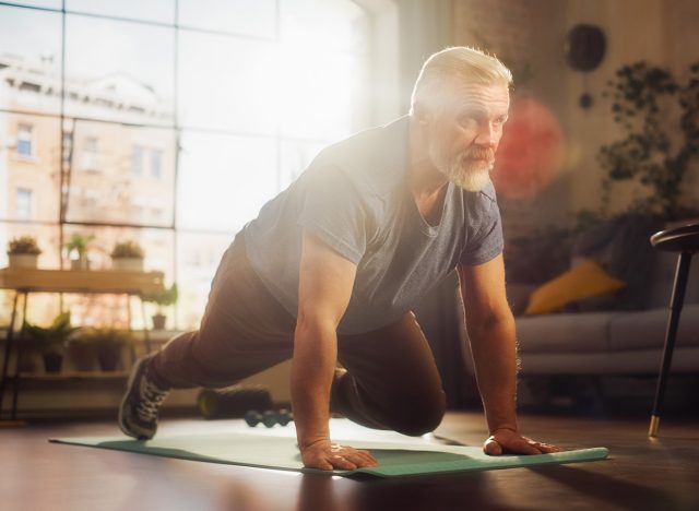 Strong Athletic Fit Middle Aged Man Doing Mountain Climber Exercises During Morning Workout at Home in Sunny Apartment. Healthy Lifestyle, Fitness, Recreation, Wellbeing and Retirement.