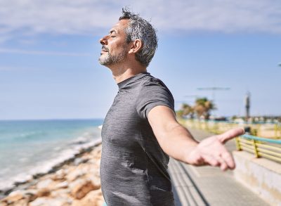 Middle age hispanic man wearing sportswear breathing at seaside