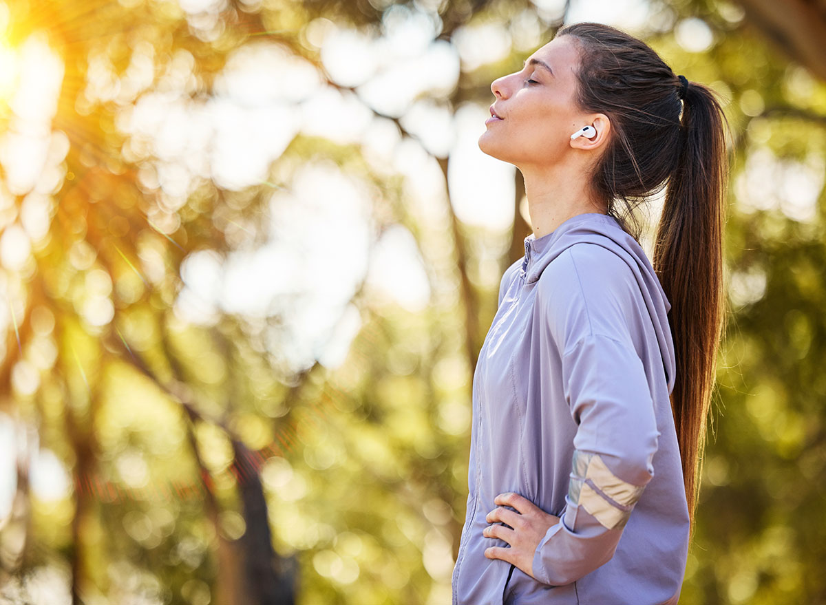 Calm, music and fitness person in nature for mental health, wellness and breathing, forest trees and fresh air. Mockup, sports and athlete woman thinking or listening to audio for running inspiration