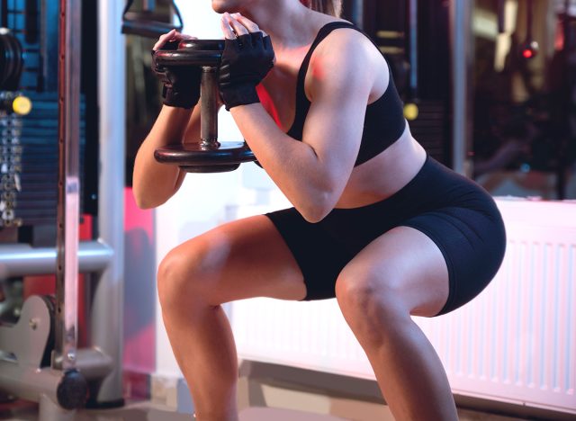 One woman doing goblet squat exercise in a gym with a dumbbell