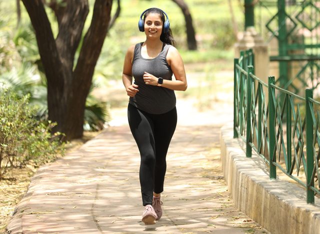 Indian happy women doing joking running and walking in garden ramp with headphone listening music feeling good