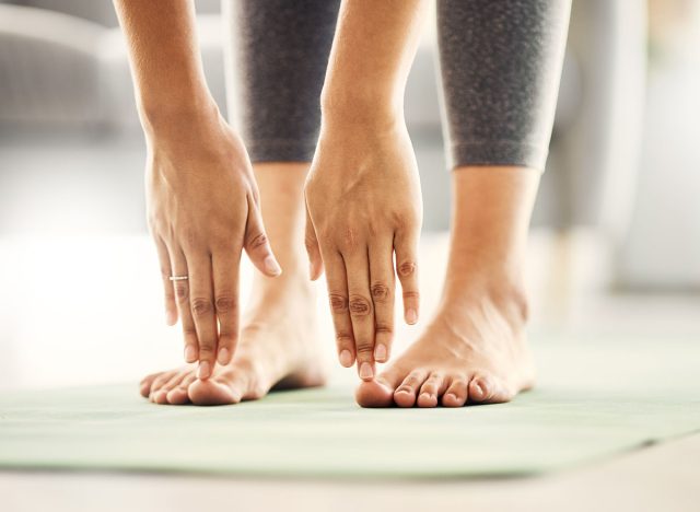 Fitness, yoga and closeup of a woman stretching before a workout for health, wellness and flexibility. Calm, breathing and zoom of female person touching her toes before pilates exercise in her home.