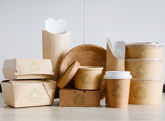 A set of disposable tableware made of cardboard and paper with recycling signs. Packaging for food delivery or for a picnic made from environmentally friendly materials.