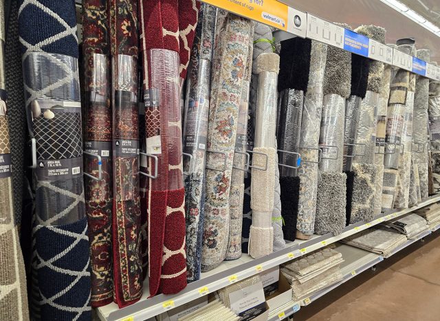 A batch of large rugs displayed along an aisle for sale.