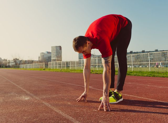 Athlete warming and stretching, touching toes 