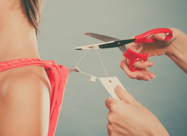 Woman girl removing cutting label board price tag off new dress cloth with scissors. Female after shopping. Instagram filter.