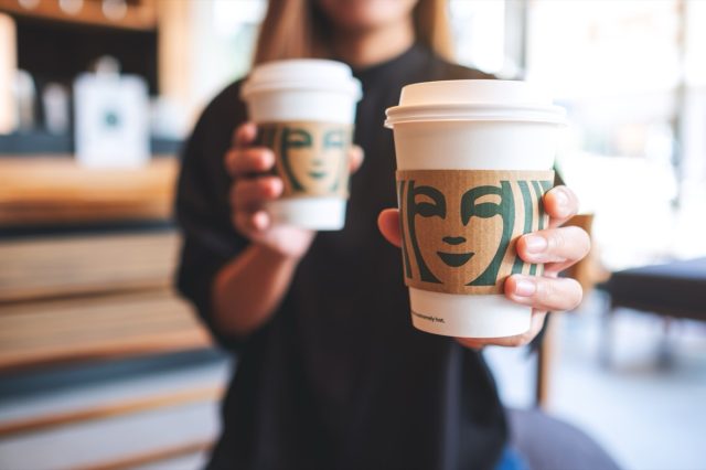 Jun 13th 2022 : Closeup of a woman holding and serving two cup of hot coffee at Starbucks coffee shop, Chiang mai Thailand