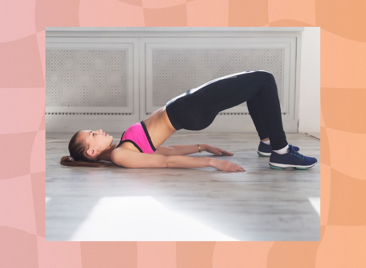 fit, focused woman doing glute bridge on floor in bright living space or workout studio