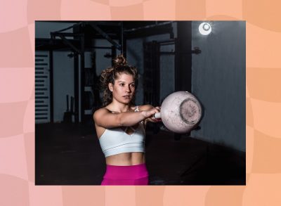 fit, focused woman doing kettlebell swing in dark gym