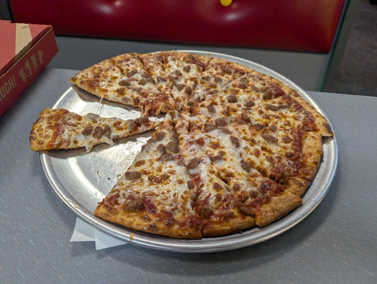 Honolulu - August 15, 2024: A freshly baked pizza sits on a metal tray, with a few slices taken, ready to be enjoyed at a lively Chuck E. Cheese venue in Hawaii.