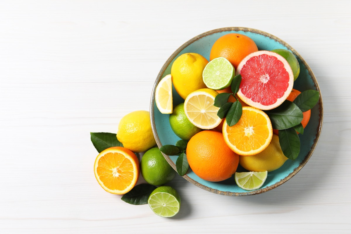 Different cut and whole citrus fruits on white wooden table, top view. Space for text