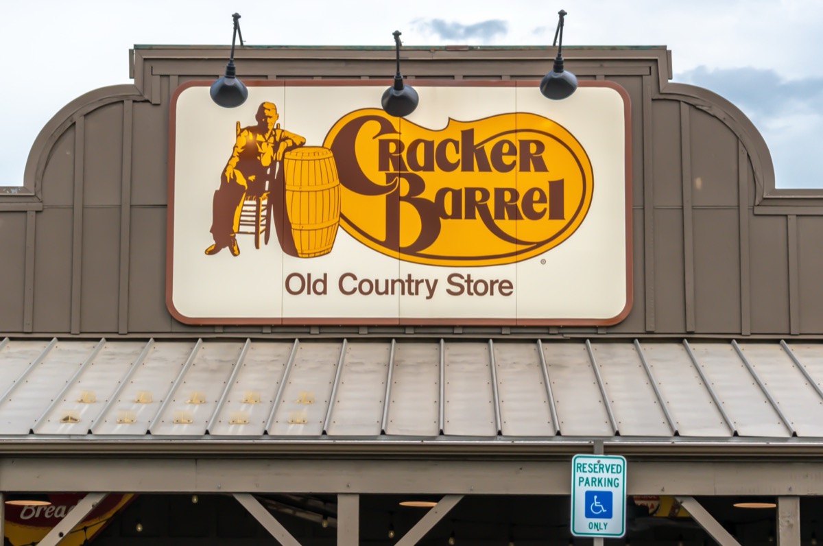 Roseville, MI USA - September 26, 2021: Horizontal, medium closeup of "Cracker Barrel" restaurant's exterior facade brand and logo signage above building overhang with light blue, cloudy sky.