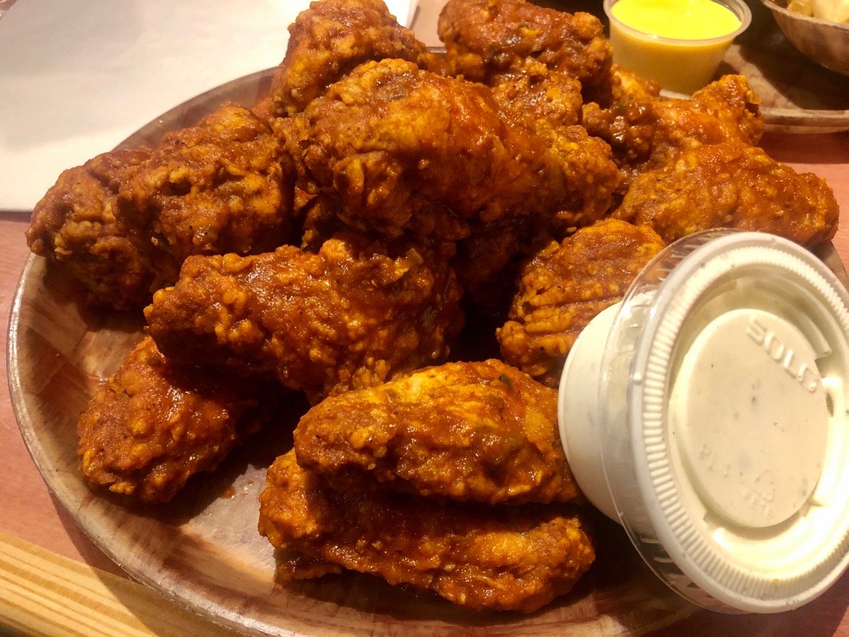 Downers Grove, IL / USA - 7/17/2020 : HOOTERS - Original Style Bone-In Wings with 9-1-1 sauce all over them. Side of Bleu Cheese. Served on a wooden platter.