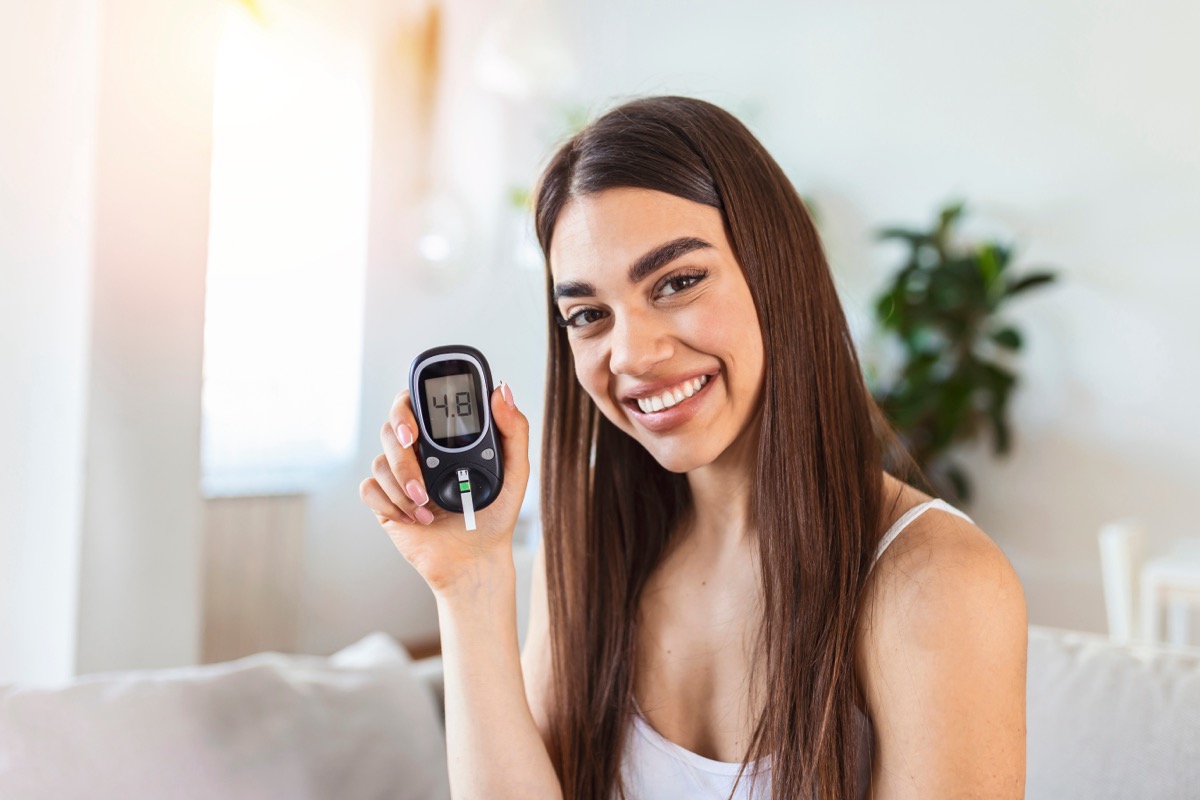 Blood sugar testing at home. Checking Blood Sugar Level At Home. Diabetic Checking Blood Sugar Levels. Woman checking blood sugar level by glucometer and test stripe at home