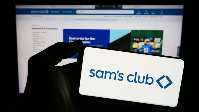 Stuttgart, Germany - 02-07-2023: Person holding mobile phone with logo of American membership-only retail stores company Sam's Club in front of web page. Focus on phone display. Unmodified photo.