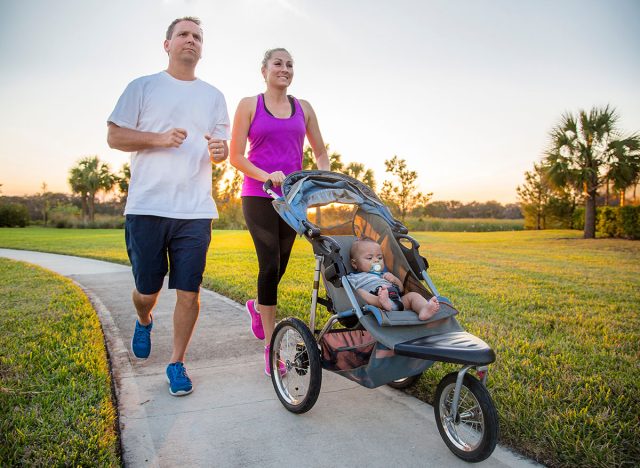 Couple exercising and jogging together at the park pushing their baby in a stroller